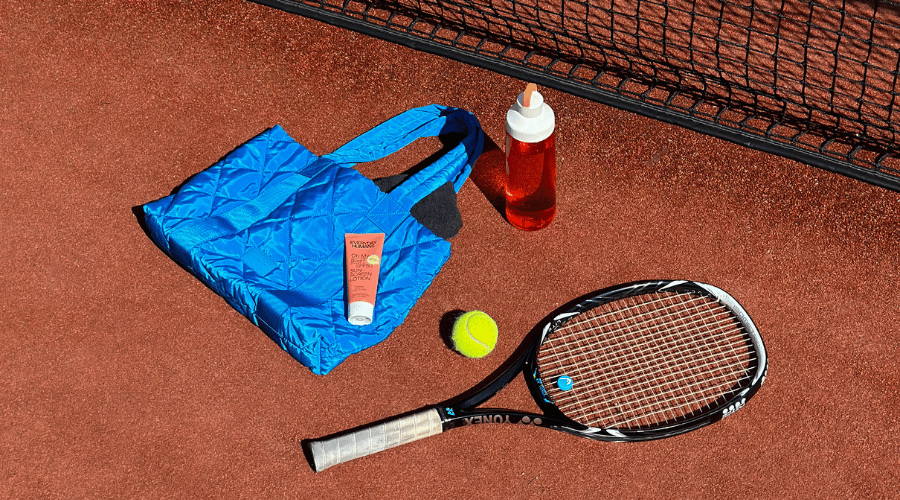 Tennisuitrusting en Oh My Bod! van Everyday Humans op een tennisbaan, passend bij de blog over de juiste skincare routine voor je workout.