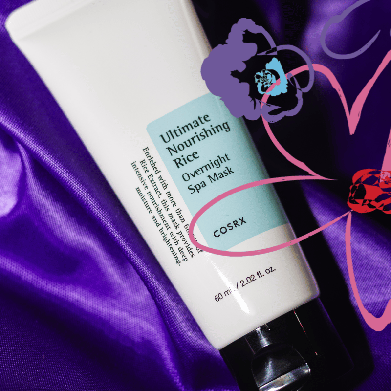 Translation missing: nl.Close-up afbeelding van de COSRX Ultimate Nourishing Rice Overnight Spa Mask tube, liggend op een paarse satijnen achtergrond. De tube heeft een witte kleur met een turquoise label waarop de productnaam in zwarte letters staat