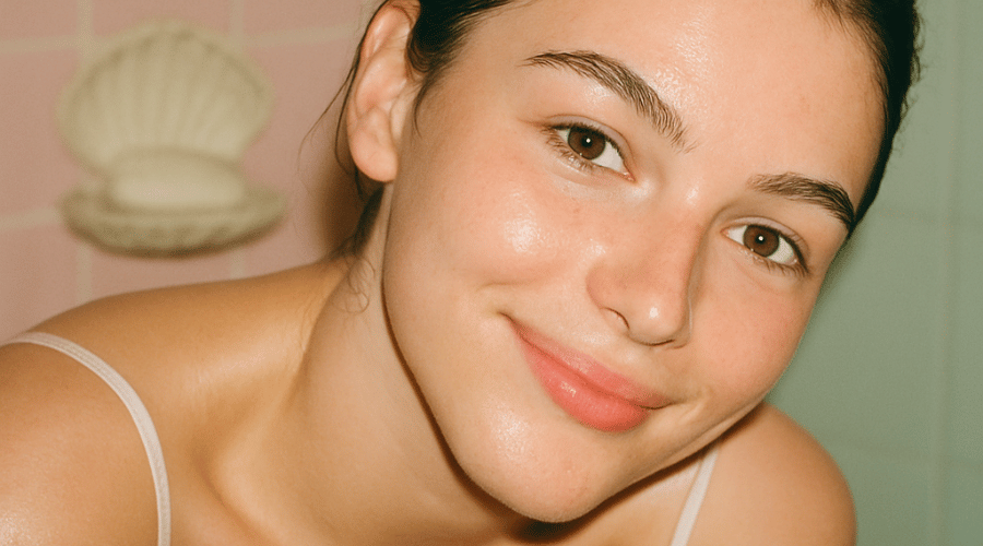 Jonge vrouw met schuimende cleanser op haar gezicht naast tekstblok “Waarom BYBI Skincare?” met drie kernpunten: botanische actives, simpel routine‑denken en 100 % vegan & planet‑positive.