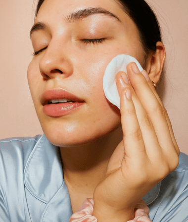 Vrouw dept haar gezicht zachtjes met een wattenschijfje gedrenkt in COSRX Centella Toner, perfect voor de gevoelige huid.