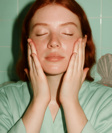Vrouw masseert COSRX Niacinamide Serum in haar gezicht met beide handen, voor optimale absorptie en effectiviteit.