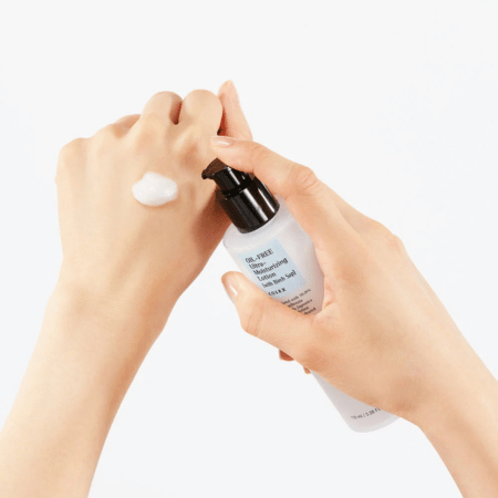 Handpomp van COSRX Oil-Free Ultra Moisturizing Lotion met een parel witte lotion op de rug van de andere hand; illustreert luchtige, olievrije textuur.
