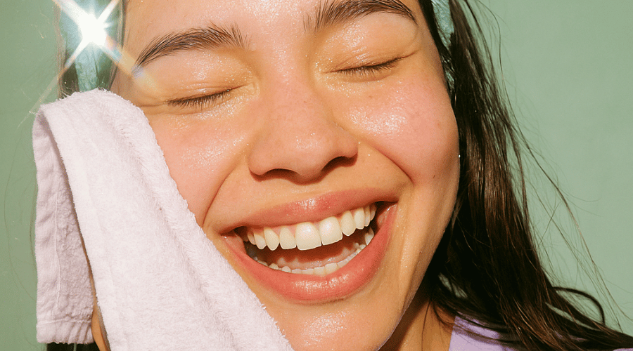 Close‑up van een lachende vrouw met dewy “glass‑skin” glow – resultaat van een Korean skincare routine.