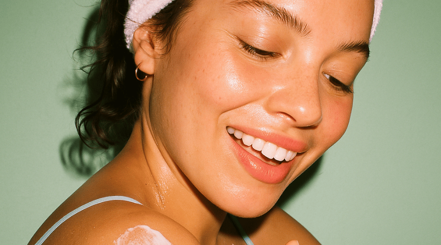 Lachende vrouw brengt zonnebrand aan – naast haar het tekstblok ‘Waarom Everyday Humans?’ met voordelen: Zachte Formules, SPF & verzorging in één, Reef‑safe & vegan.