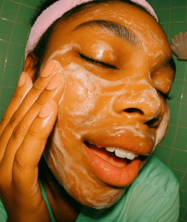 Glimlachende vrouw met haarband en volledig ingeschuimd gezicht tijdens het gebruik van Facile Gel Cleanser, toont de romige textuur.