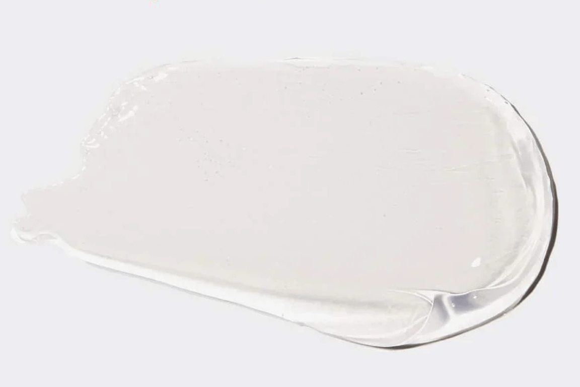 Kristalheldere gel-swatch van Lip Jelly Clear op een lichtgrijze achtergrond; toont de zuivere, niet-plakkerige textuur.