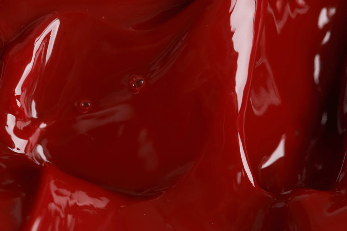 Dieprode, glanzende geltextuur van Lip Jelly Rouge; toont de rijke, smeuïge consistentie van het product.