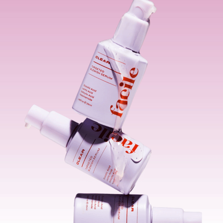 Drie flessen Facile Skin Clear Acne Serum gestapeld op elkaar tegen een lichte achtergrond, toonend de minimalistische verpakking.