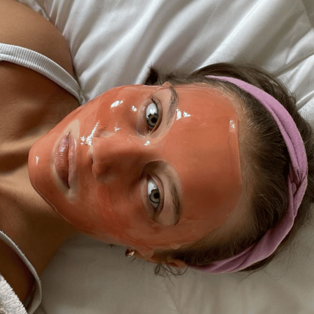 Vrouw ontspant met roze hydrogel masker op gezicht tijdens 10 minuten behandeling